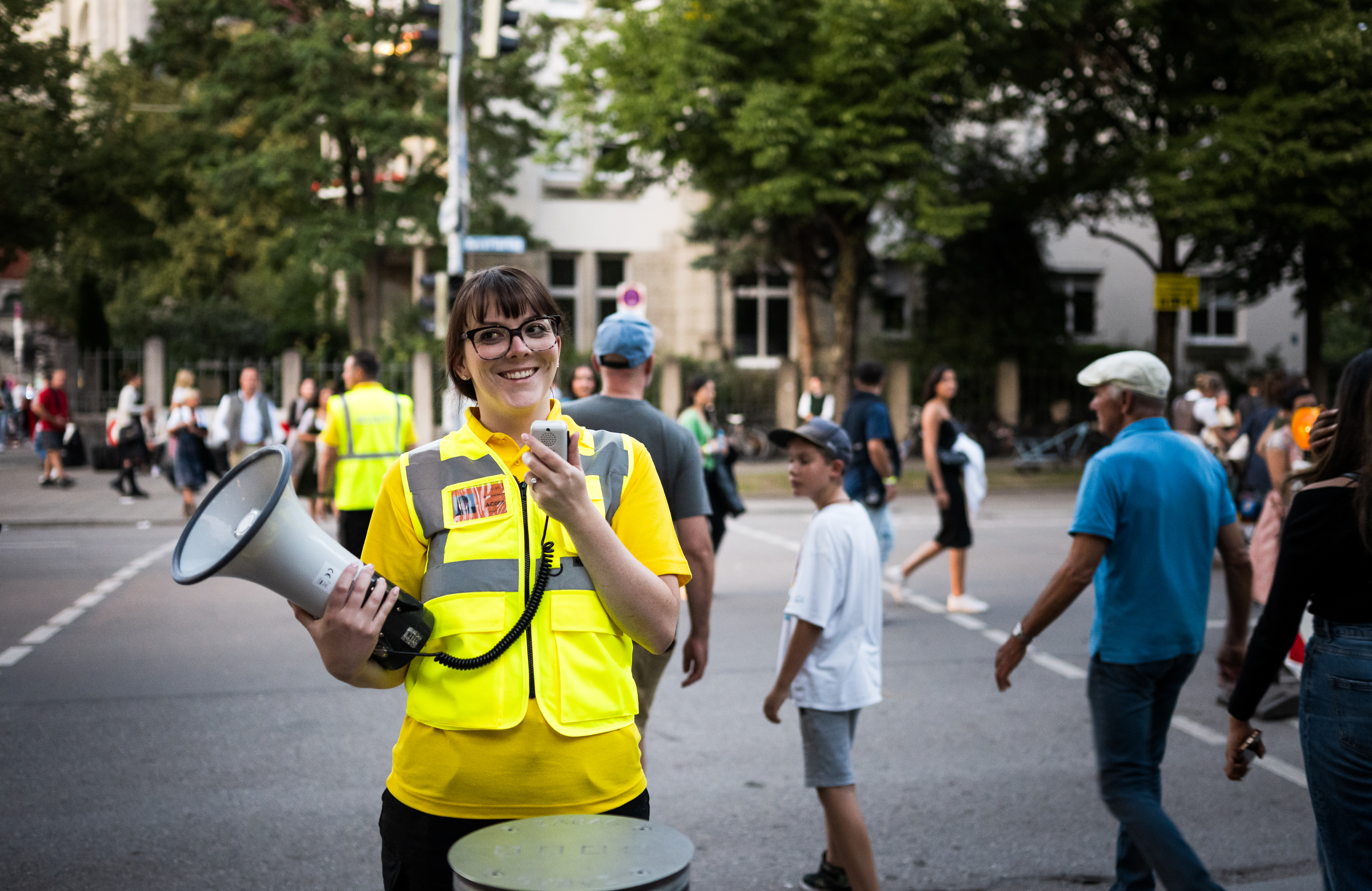 Female security guard with a megaphone on a crowded street at Oktoberfest.
